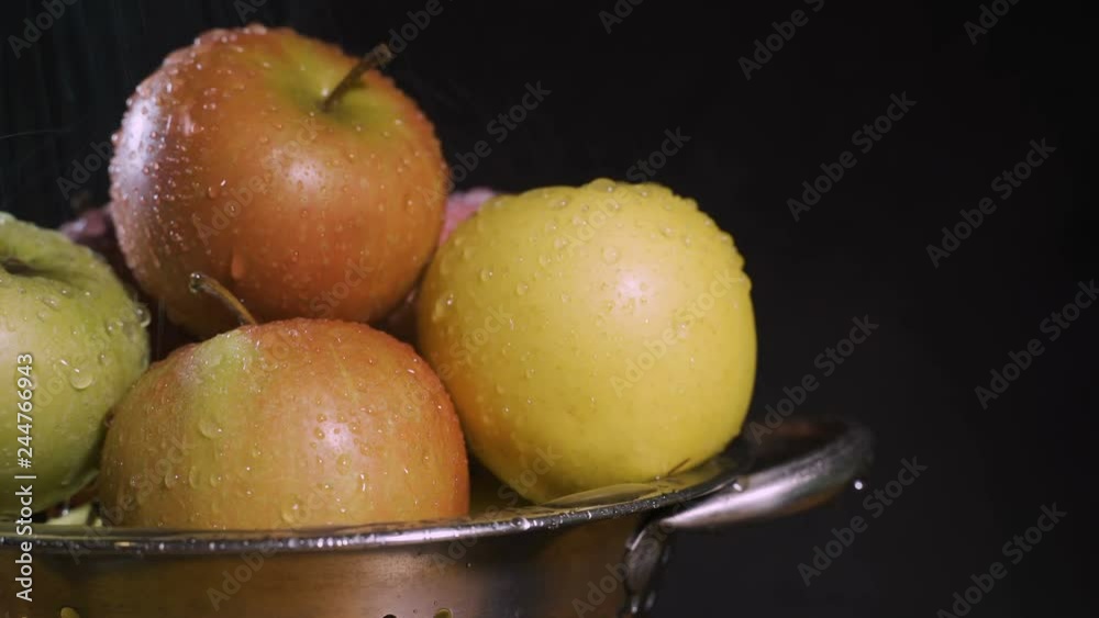 Apples wash under water jets on a black background.