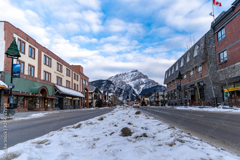 Fototapeta premium Cityscape view of Banff Avenue, a popular tourist destination in the Canadian Rockies, filled with gift shops and restaurants with Mt. Rundle in background