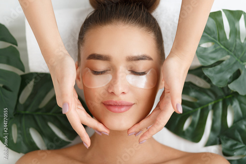 Photo Woman with eye patches having face massage