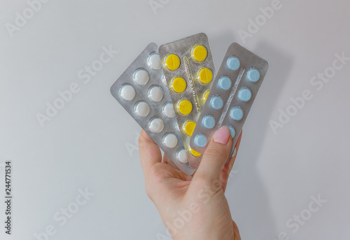 three package of white, bleu and yellow pills in hands islotaed on white background