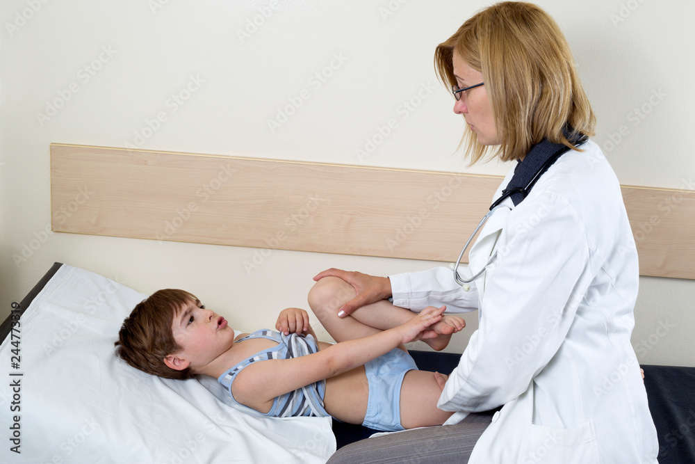 Fototapeta premium Cute Little Boy Complaining Of The Pain In His Leg To The Doctor In The Consulting Room