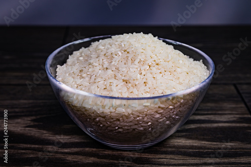 Glass bowl with rice on wooden table.