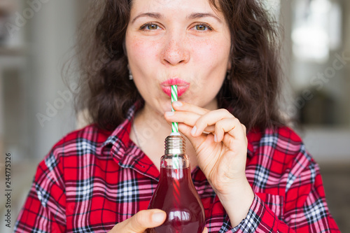Health  food  diet and people concept - young woman drinking natural juice in a bottle and it seems to be tasty
