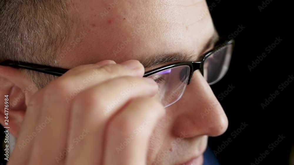 Serious thoughtful man in a business suit puts on glasses close-up. Entrepreneur, manager. Work at the computer. Vision. View from above. Serious thoughtful man in a business suit puts on glasses close-up. Entrepreneur, manager. Work at the computer. Vision. View from above.