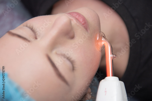 Obraz na plátně Receiving electric darsonval facial massage procedure at beauty salon