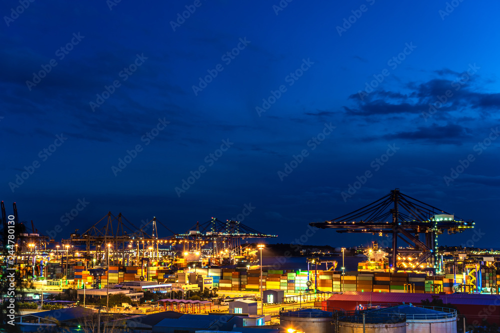 Container Cargo freight ship with working crane bridge in shipyard at dusk Container Cargo freight ship with working crane bridge in shipyard at dusk