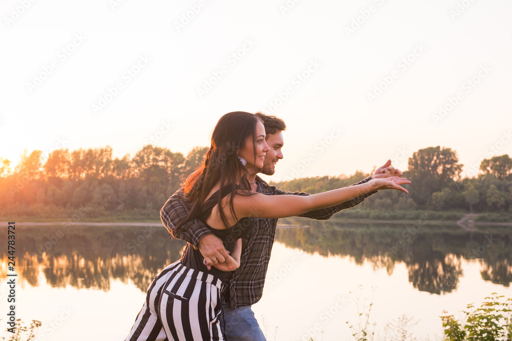Romantic, social dance and people concept - young couple dancing a tango or bachata near the lake