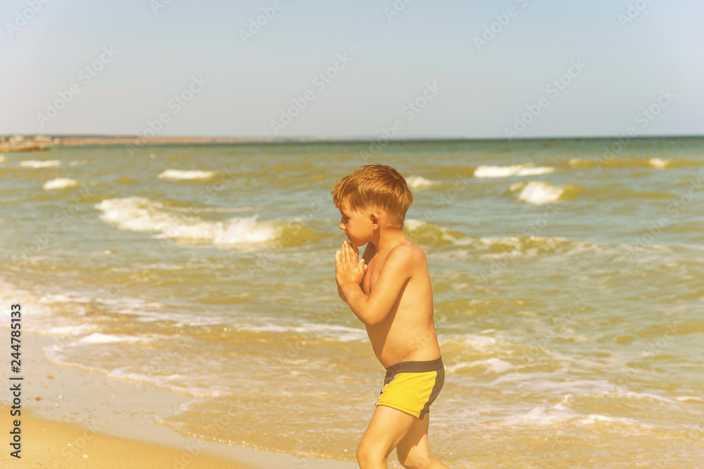 The boy comes out of the water after swimming on the beach in summer on holidays The boy comes out of the water after swimming on the beach in summer on holidays