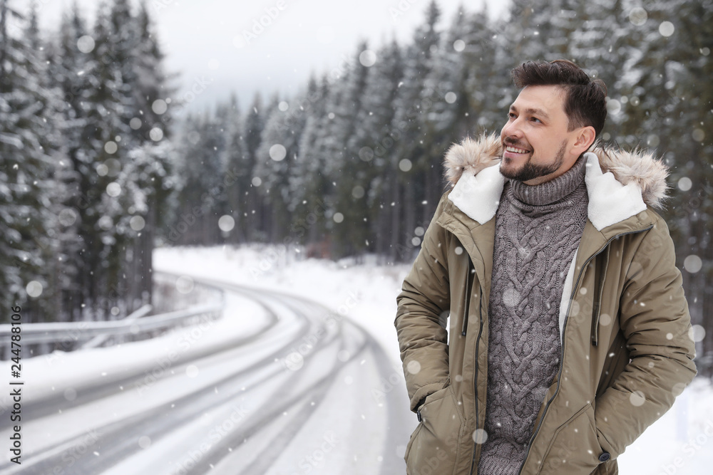 Man in warm clothes near snowy forest, space for text. Winter vacation Man in warm clothes near snowy forest, space for text. Winter vacation