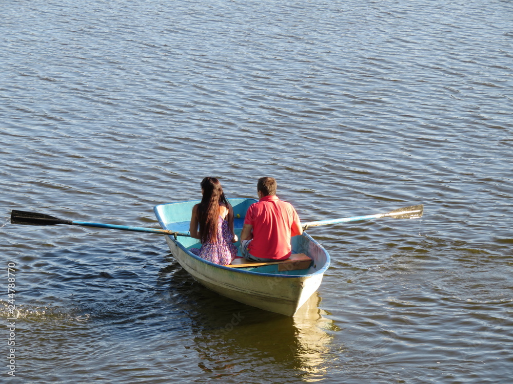Rowing boat with couple in love. Young man and girl boating on a lake, concept of romantic date, leisure on the water Rowing boat with couple in love. Young man and girl boating on a lake, concept of romantic date, leisure on the water