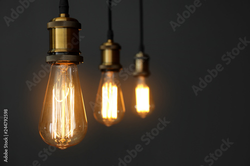 Pendant lamps with light bulbs on grey background. Space for text photo