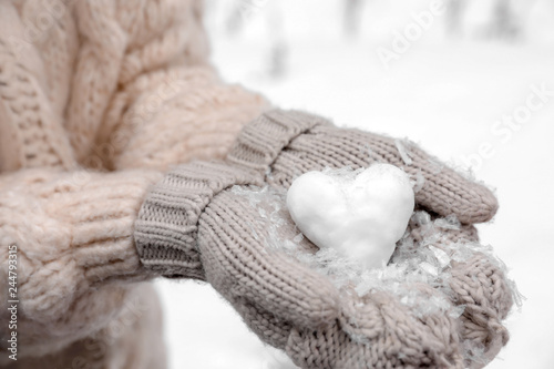 Woman holding heart made of snow, closeup view