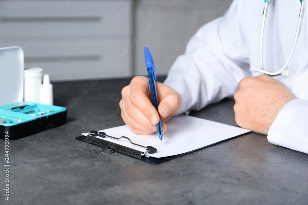 Doctor writing at table with different medical objects, closeup Doctor writing at table with different medical objects, closeup