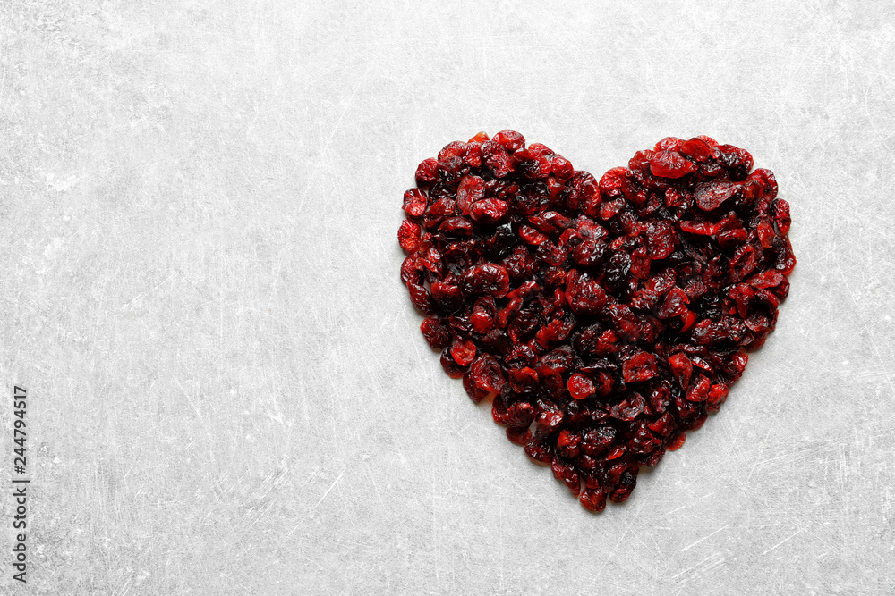 Heart shaped heap of sweet cranberries on color background, top view with space for text. Dried fruit as healthy snack Heart shaped heap of sweet cranberries on color background, top view with space for text. Dried fruit as healthy snack