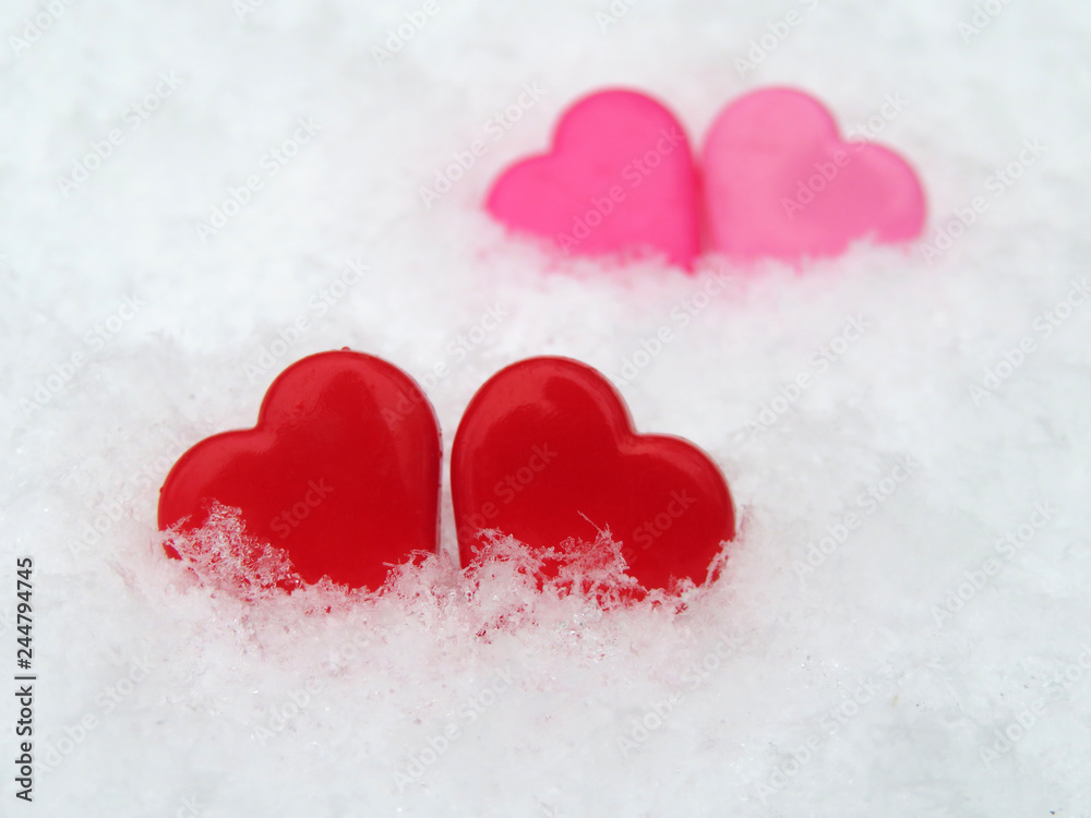 Fototapeta premium Valentine hearts in the snow, red and pink symbols of love. Background for romantic greeting card with free copy space