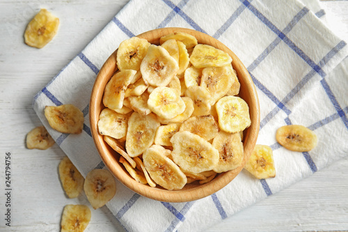 Wooden bowl with sweet banana slices on table, top view. Dried fruit as healthy snack