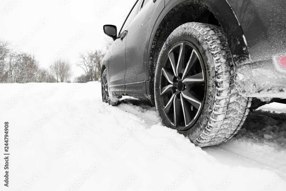 Snowy country road with car on winter day, closeup. Space for text
