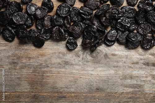 Dried plums on wooden background, top view with space for text. Healthy fruit