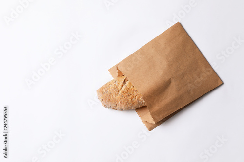Paper bag with bread on white background, top view. Space for text