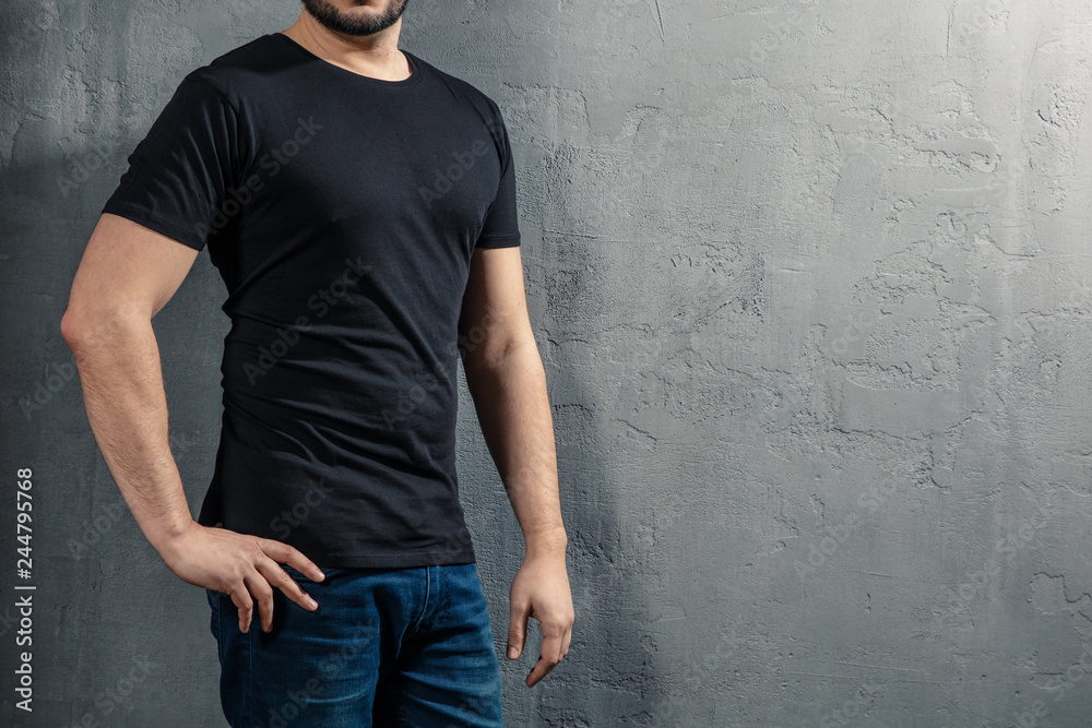 Young healthy man with black T-shirt on concrete background with copyspace for your text. Picture without model face. Young healthy man with black T-shirt on concrete background with copyspace for your text. Picture without model face.