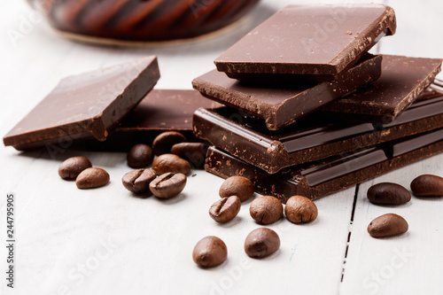 pieces of dark chocolate and coffee beans on a white table