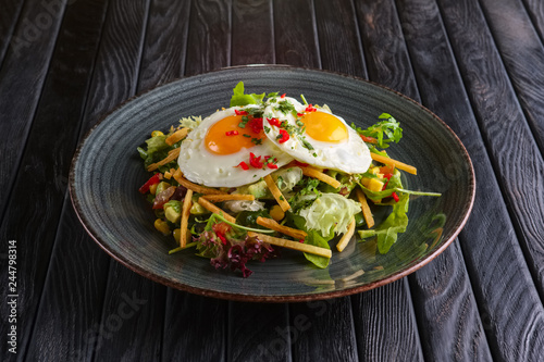Fried eggs with avocado, salad leaves and crispy chips