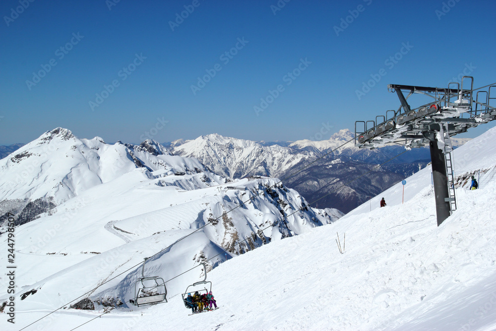 Fototapeta premium Skiers and snowboarders on chairlift, ski resort Rosa Khutor, Sochi Russia