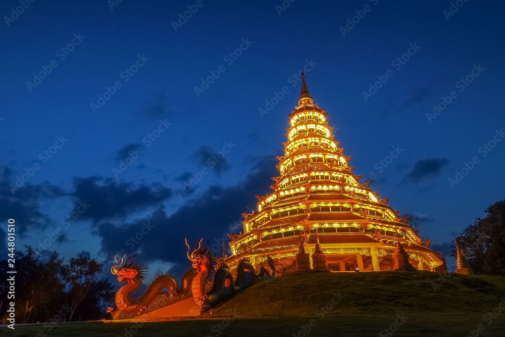 Fototapeta premium Wat Huay Pla Kang, beautiful golden pagoda chinest style decorate with lighting at night with cloudy sky background, chinese temple in Chiang Rai, Thailand.