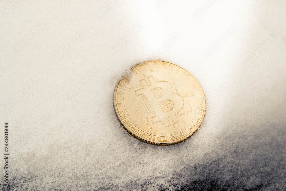 Golden bitcoin coin in snow