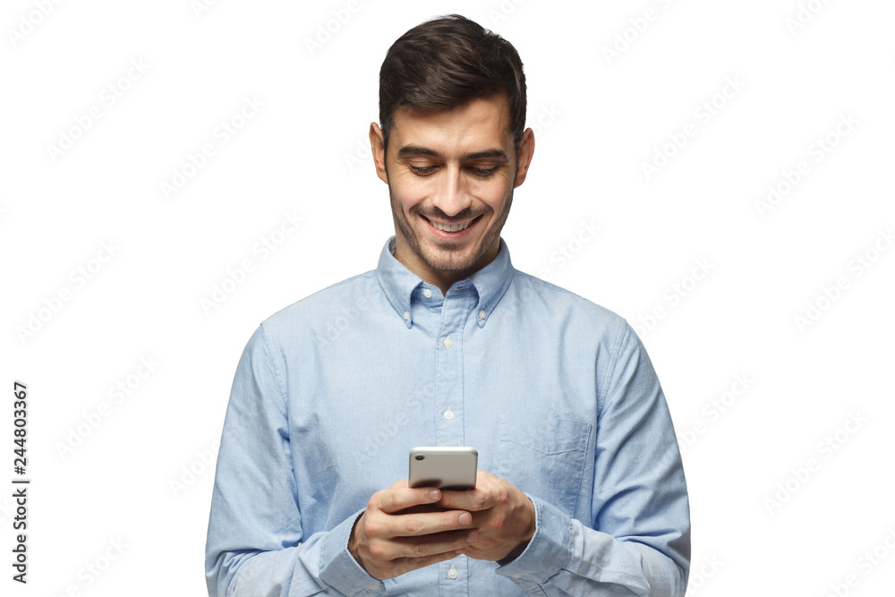 Young smiling business man in blue shirt reading sms, using smartphone, isolated on white background Young smiling business man in blue shirt reading sms, using smartphone, isolated on white background