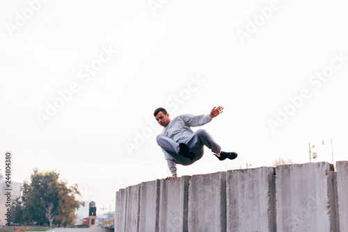 Caucasian man trains parkour while jumping over a high top.
