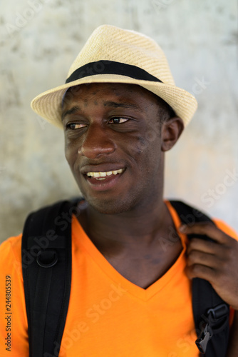 Face of happy young African tourist man smiling and thinking