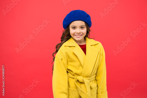 Spring fashion. Kid girl wear coat for spring season. Girl smiling face cute hairstyle fashionable spring coat with hat. Child cheerful posing wearing warm bright coat or jacket. Spring fashion trend