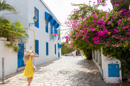 Bild auf Leinwand SIDI BOU SAID, TUNISIA - JULY 19, 2018: A woman in yellow dress walking in a cit