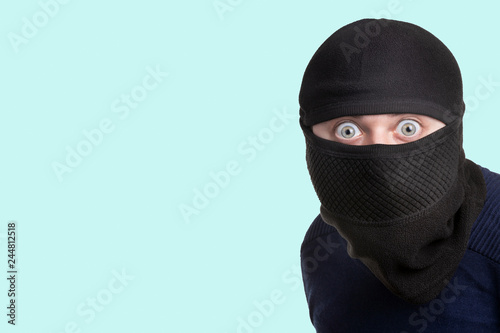 man in a balaclava on a blue background, concept of catching a criminal at a crime scene photo