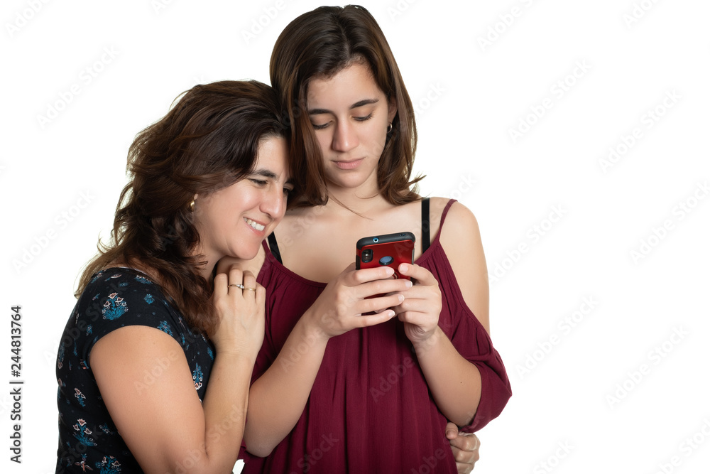 Hispanic teenage girl and her affectionate mother looking at a smartphone Hispanic teenage girl and her affectionate mother looking at a smartphone