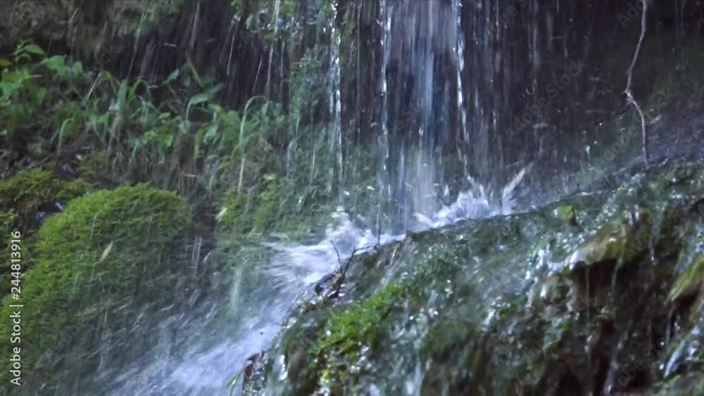 close view waterfall jets fall on stones overgrown with green moss making foamy splashes in summer close view waterfall jets fall on stones overgrown with green moss making foamy splashes in summer
