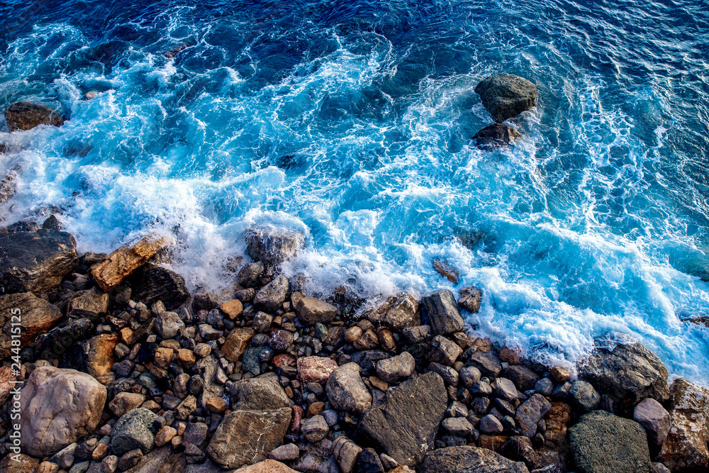 Top view aerial drone close up. Sea waves wash the wild rocky beach