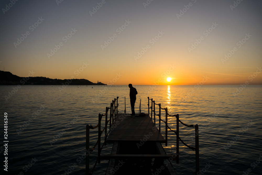 Silhouette of a man getting ready for swimming in seaside on sunset