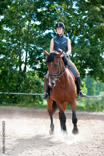 Young lady riding a horse at equestrian school. Training process © AnnaElizabeth
