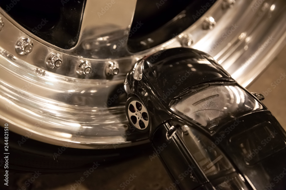 Black toy car stays on alloy rims of real car. Custom tuning wheels