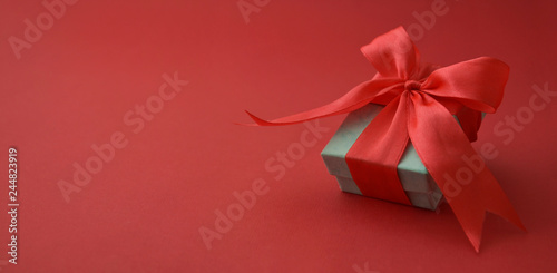 Close up gift box, birtday gift with red bow on red background. Love, Valentine's Day, Mother's Day. Banner.