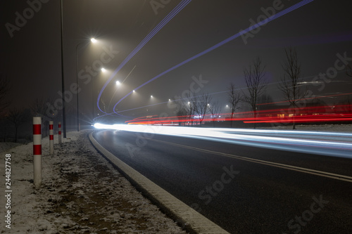 Road in a light fog illuminated by lanterns. The route is intended for the movement of passenger vehicles and trucks.