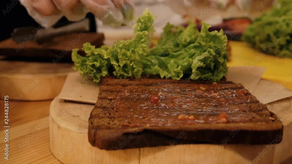 Cooking a sandwich in the kitchen. Close-up of fried black bread plastered with sauce, on which lies a green leaf of lettuce Cooking a sandwich in the kitchen. Close-up of fried black bread plastered with sauce, on which lies a green leaf of lettuce
