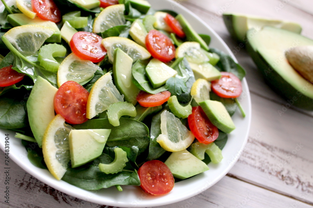 Fresh salad with spinach, avocado, tomato and lemon. Diet food. Top view with copy space. Vegetarian and vegan gosh. Fresh salad with spinach, avocado, tomato and lemon. Diet food. Top view with copy space. Vegetarian and vegan gosh.