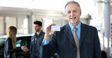 Happy male car dealer holding a business card