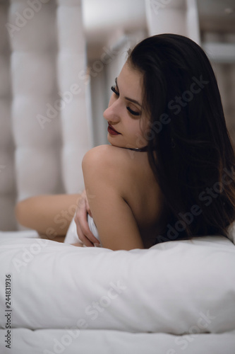 Portrait of a lovely woman lying on the bed and looking at camera