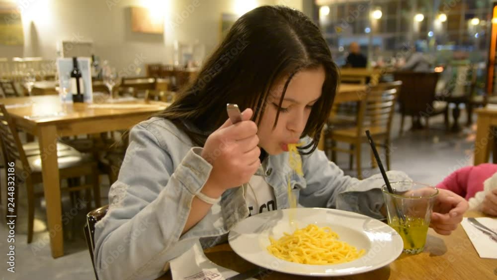 Child eats spaghetti pasta in the restaurant. Low light selective focus. Child eats spaghetti pasta in the restaurant. Low light selective focus.