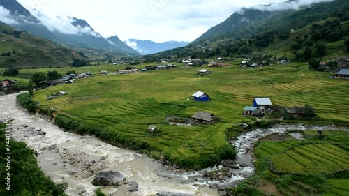 River in Sapa, Vietnam with a view on the paddy fields and few houses surrounded by mountains near Cat Cat village and a cloudy, calm weather photo