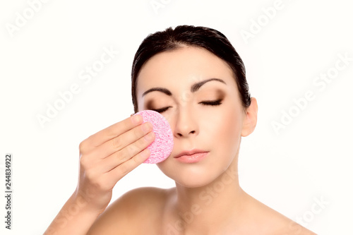 Beautiful Young Woman clean own face on the white background. Facial beauty treatment . Cosmetology and spa .